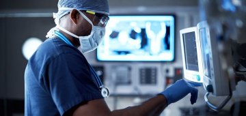 Doctor with mask on in front of medical monitoring device