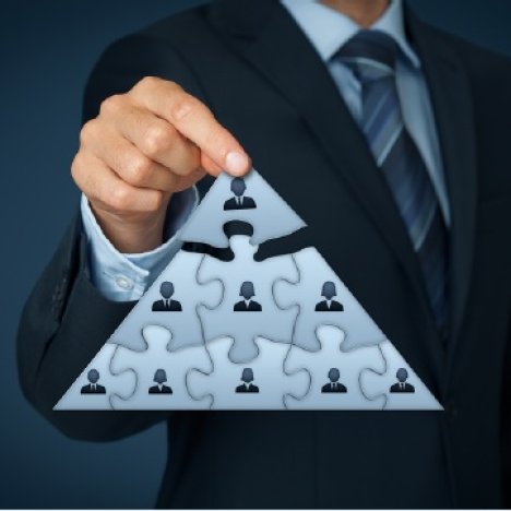 Business man holding up a puzzle piece shaped like a pyramid