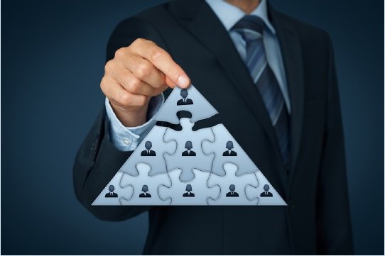 Business man holding up a puzzle piece shaped like a pyramid