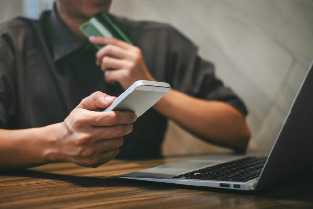 Man Hands Hold Smartphone Credit Card and Using a Laptop